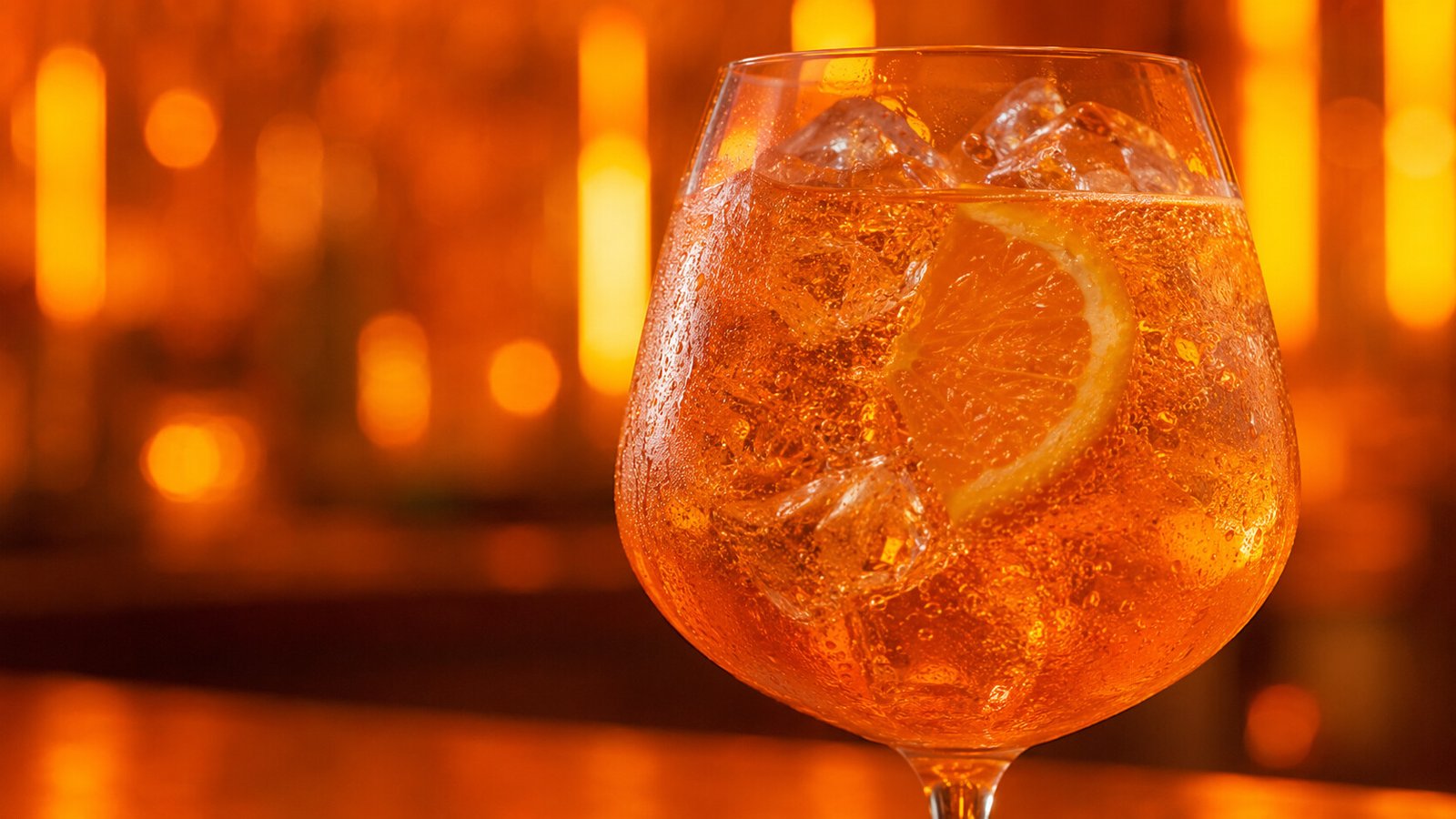 Alkoholfreier Aperol Spritz im Glas vor farbigem Neonlicht