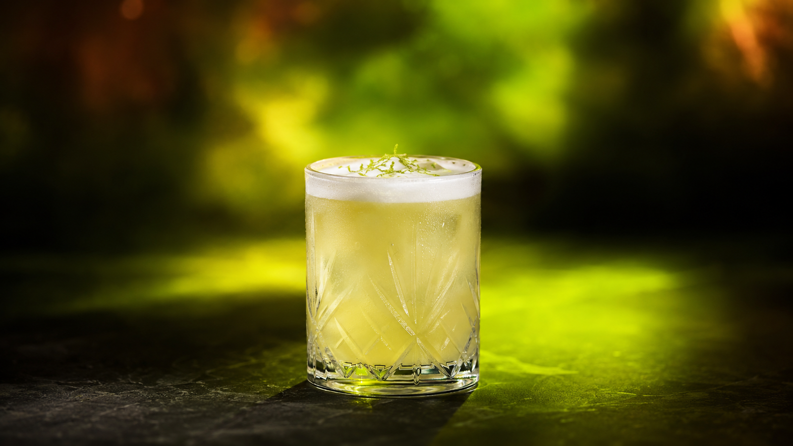 Tequila Sour vor extrem unscharfem Neonhintergrund in der Farbe des Drinks